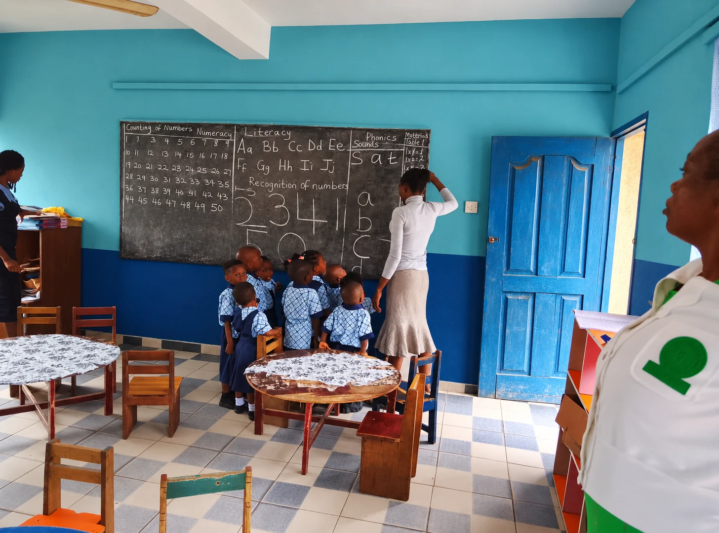 A teacher guiding young pupils at the classroom board